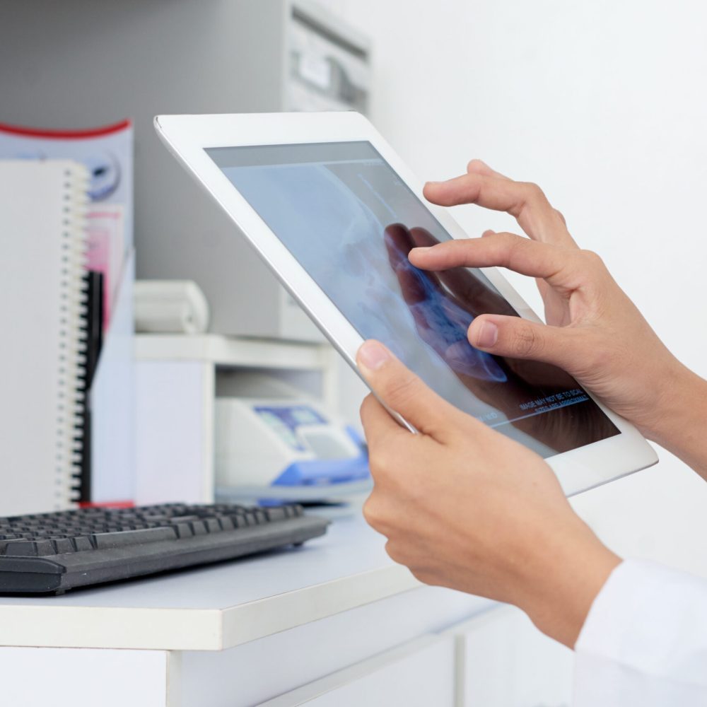 Hands of nurse examining jaw x-ray on the screen of digital tablet